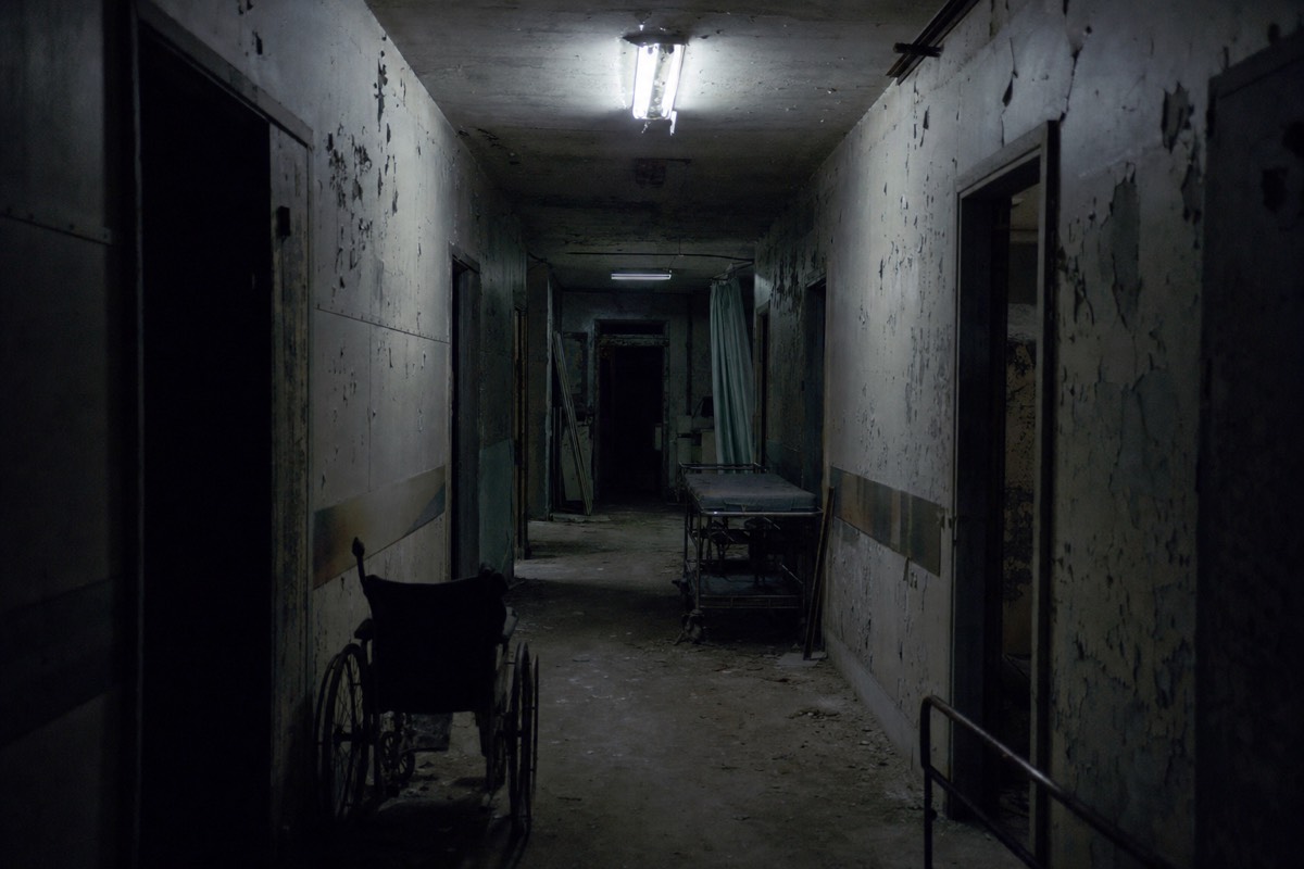Dim hospital corridor with flickering light, part of a walking horror attraction