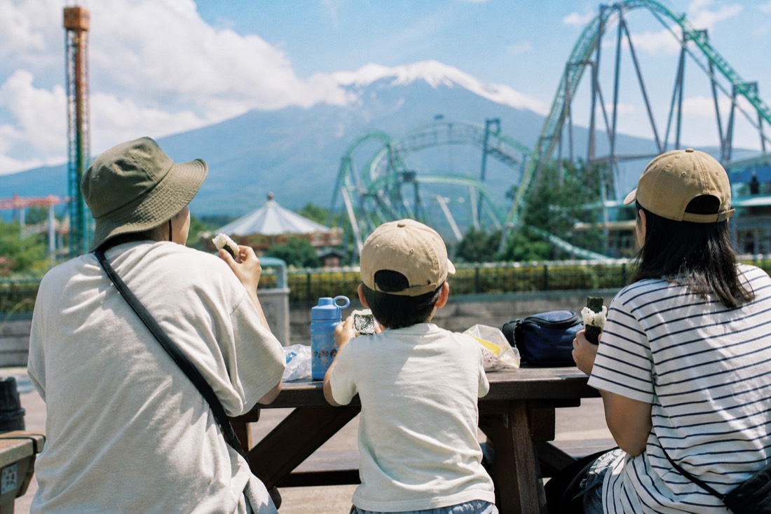 A family eating packed rice balls at an outdoor Fuji-Q Highland picnic table