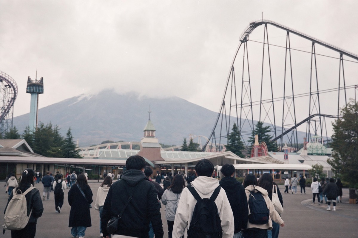 Visitors walking toward the Fuji-Q Highland entrance gates on a clear morning
